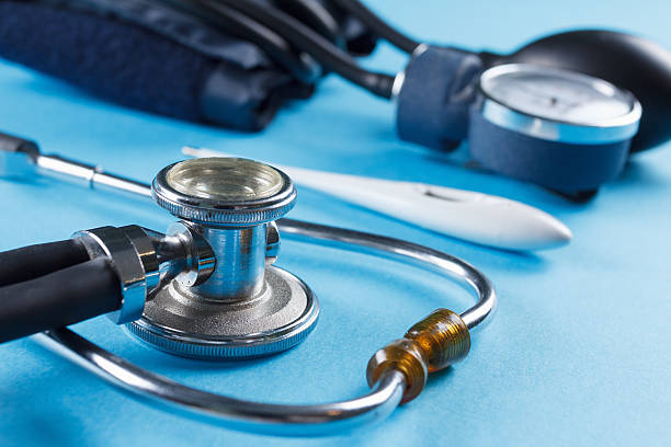 Medical devices stethoscope, tonometer, and thermometer on blue background