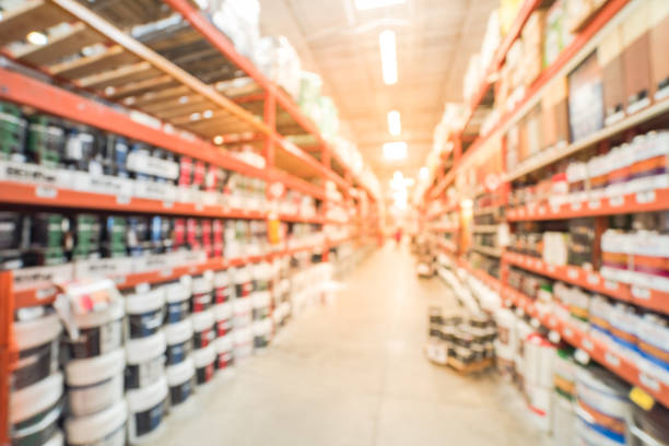 Blurred large hardware store in USA. Defocused interior home improvement retailer, racks, rows of interior paint, exterior paint/stain, floor paint/stain cans and building materials, customer shopping